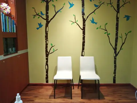 Sala de espera con mural de árboles y pájaros